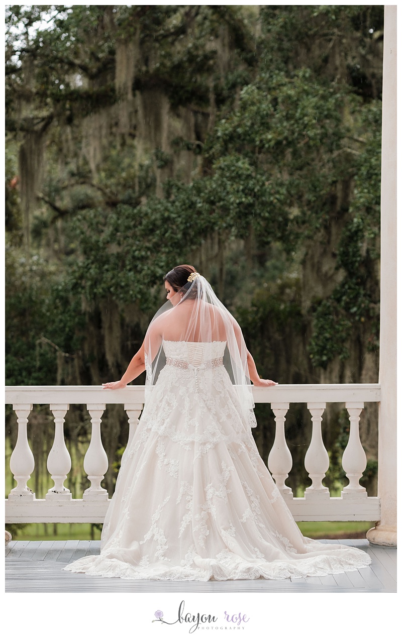 Bride against railing with Spanish moss behind her