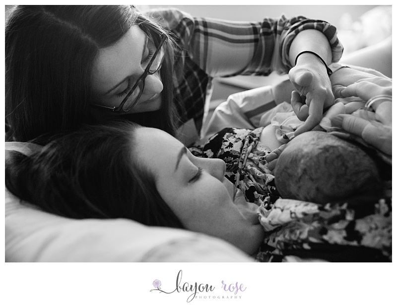two moms hold newborn baby