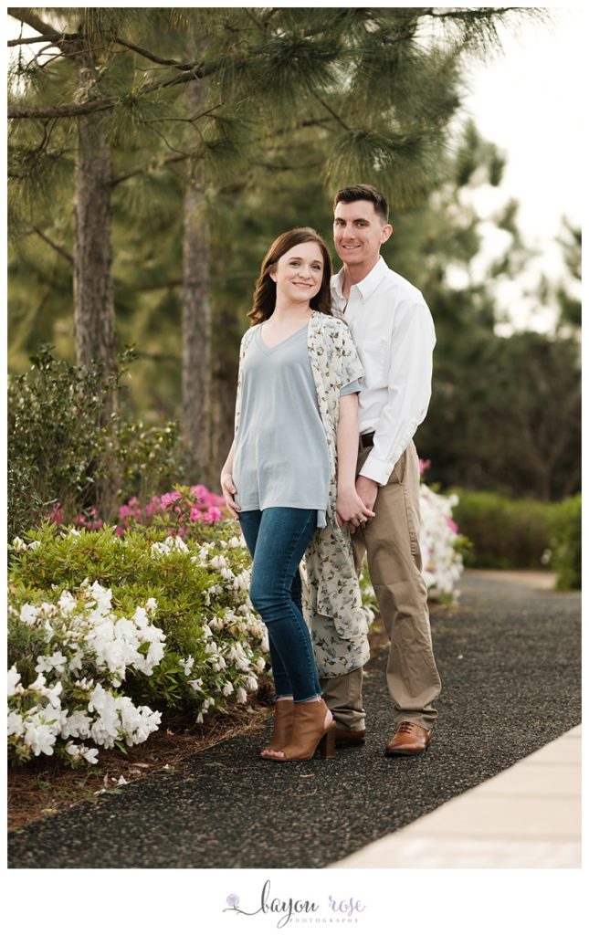 Couple posing for engagement photos in a garden area of New Orleans