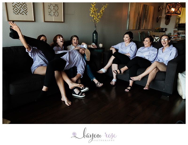 Bridesmaids laugh while sitting on couch