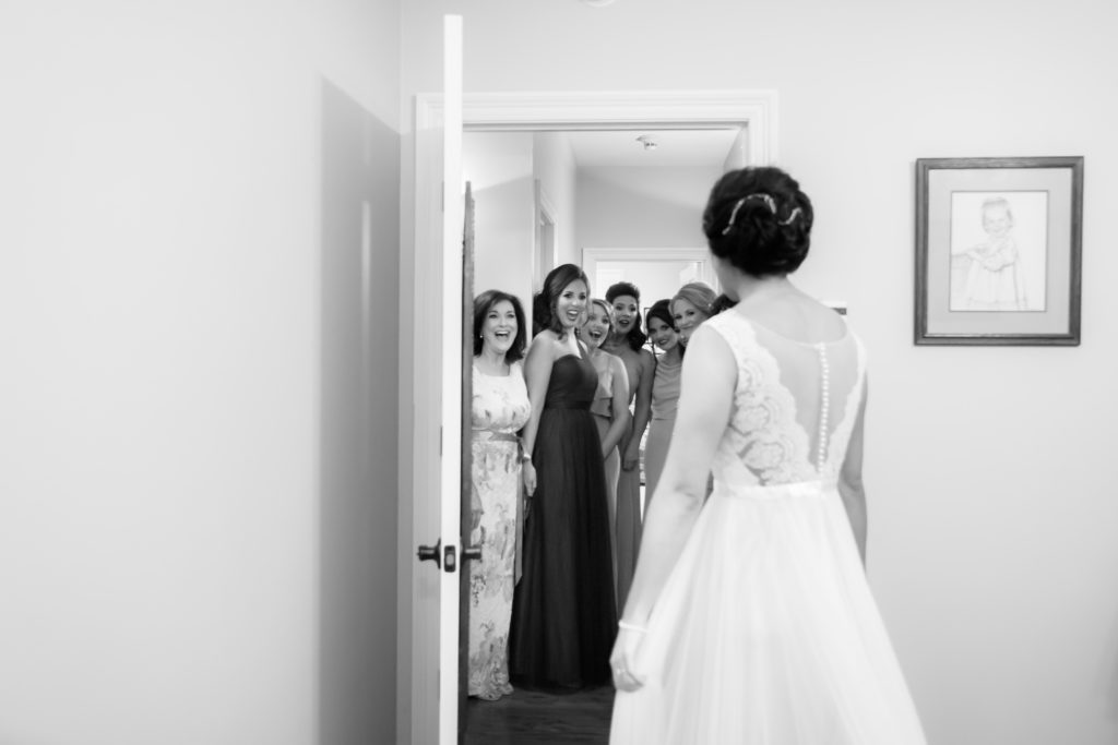 Bridesmaids smile as they see bride's dress for first time
