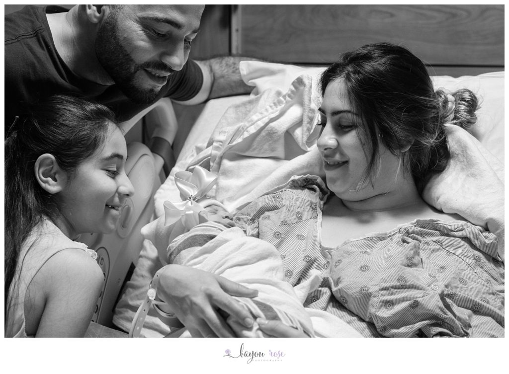family smiles at newborn baby
