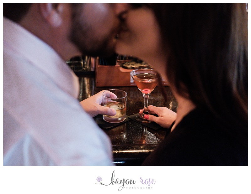 couple holds drinks in a bar and kisses