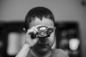 black and white image of an the Baton Rouge photographer's autistic son holding a car in front of his face
