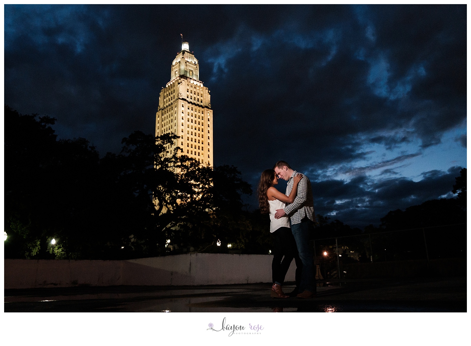 Couple against stormy sky with Baton Rouge capitol in background