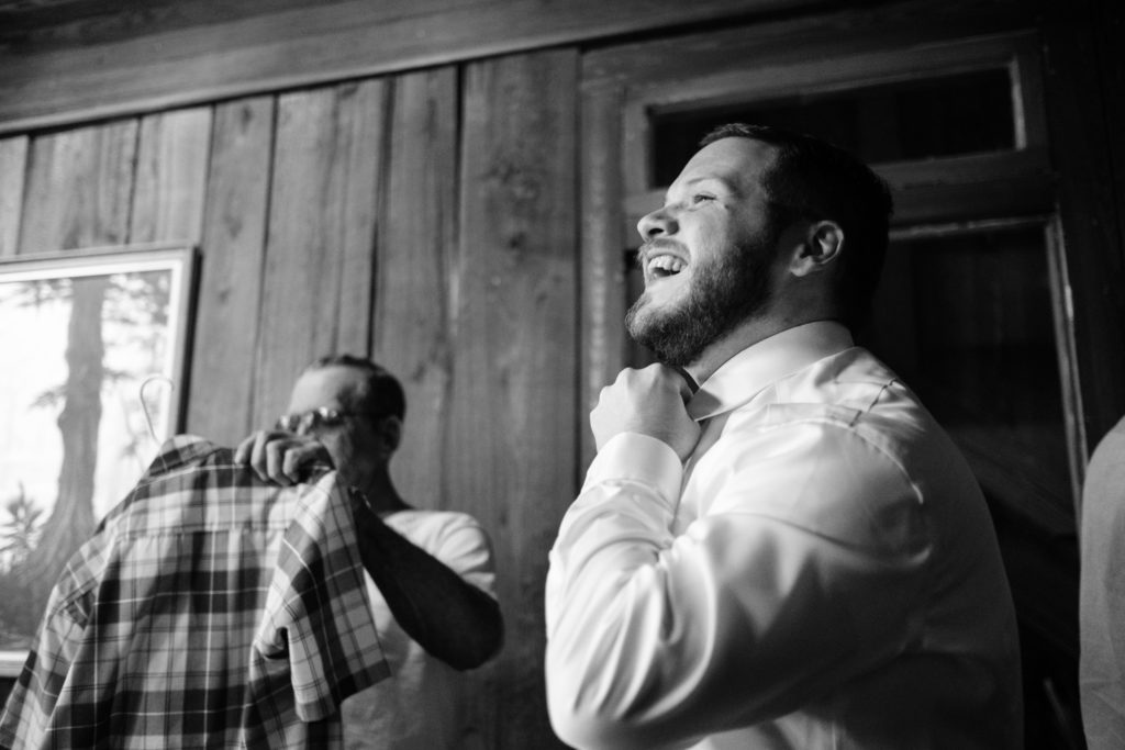groom laughing as he gets ready