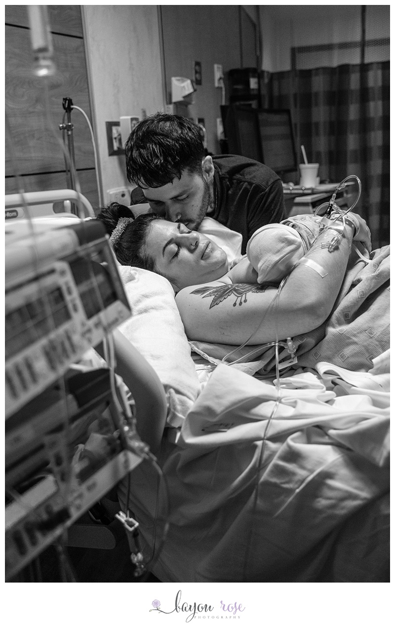 dad kisses mom as she holds newborn baby