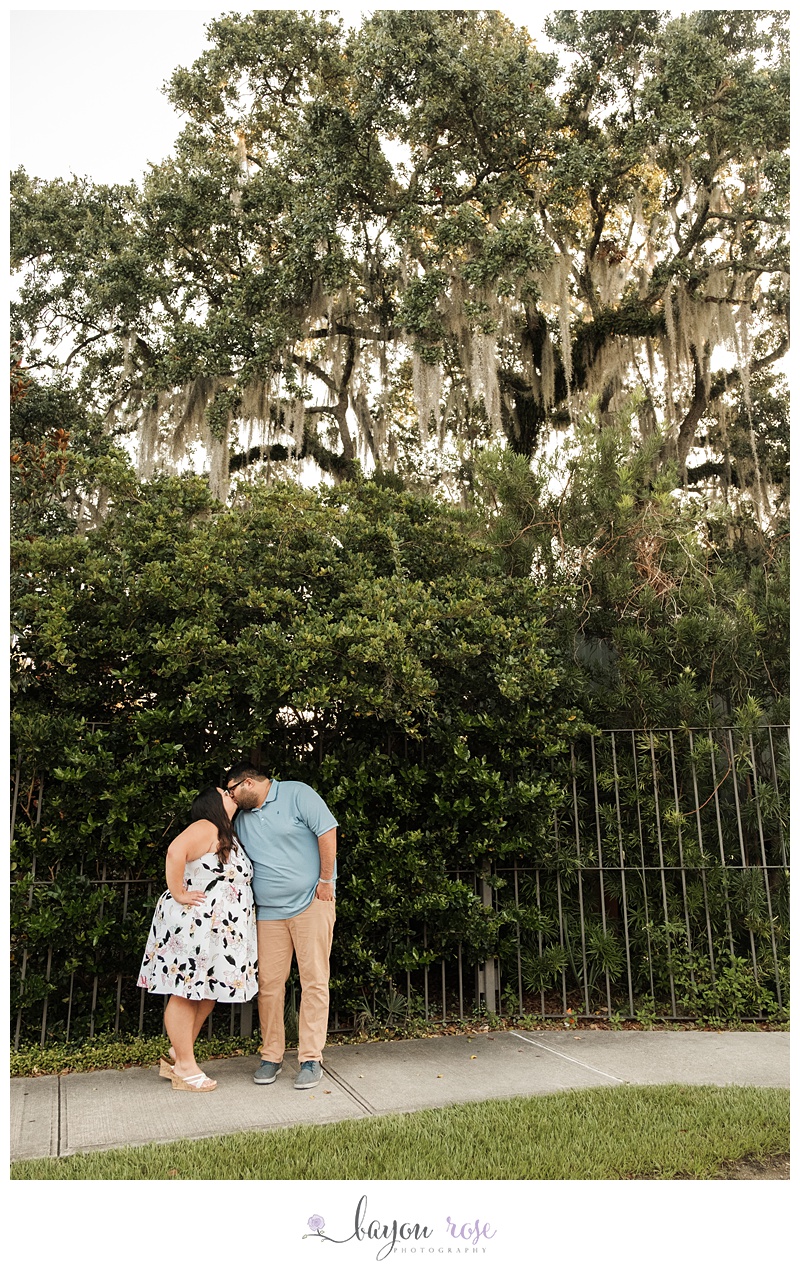 Engaged couple kissing under Spanish moss trees at City Park