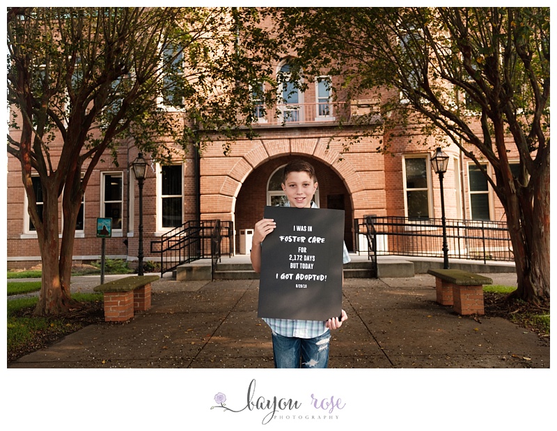 boy holds sign announcing adoption
