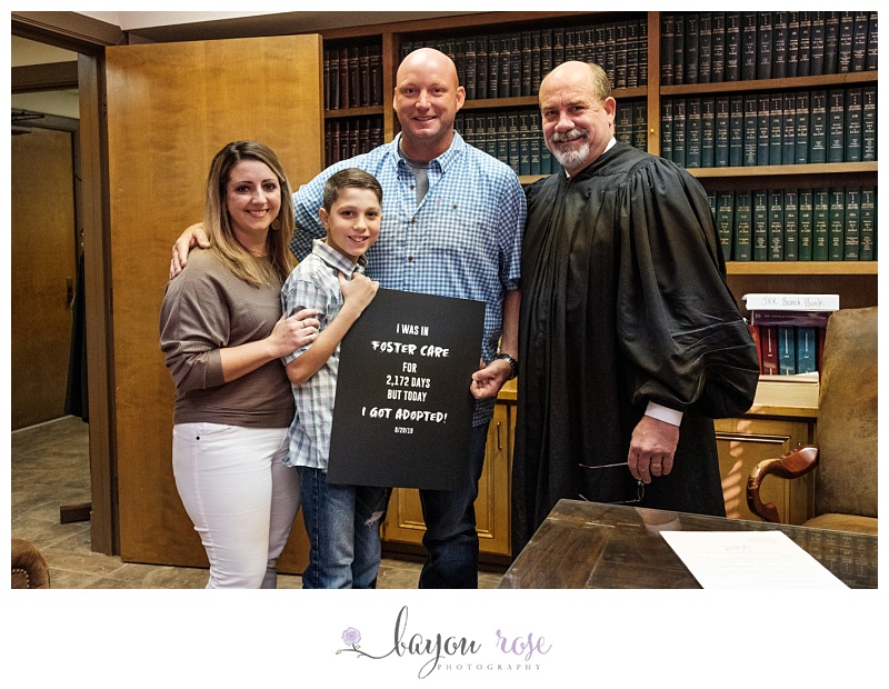 family poses with judge and sign