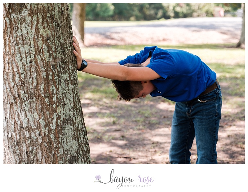 boy stops to catch  breath leaning against tree