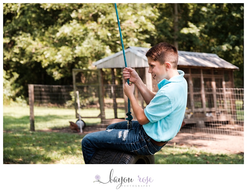 boy in blue shirt swings on tire swing and laughs