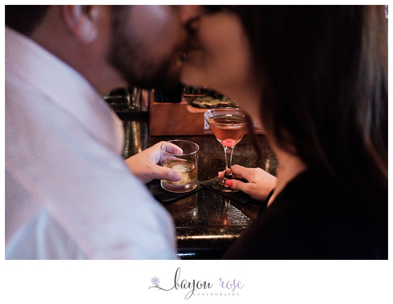 Image of drinks on bar with couple kissing in foreground