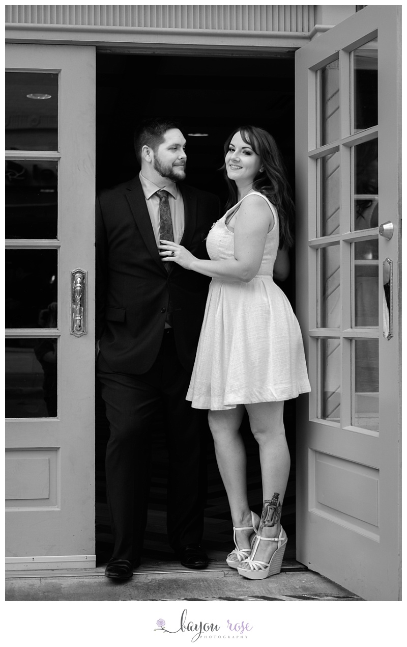 couple poses for engagement photo in doorway of hotel