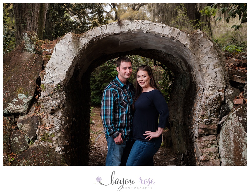 couple smiling and posing under archway of grotto surrounded by Spanish moss
