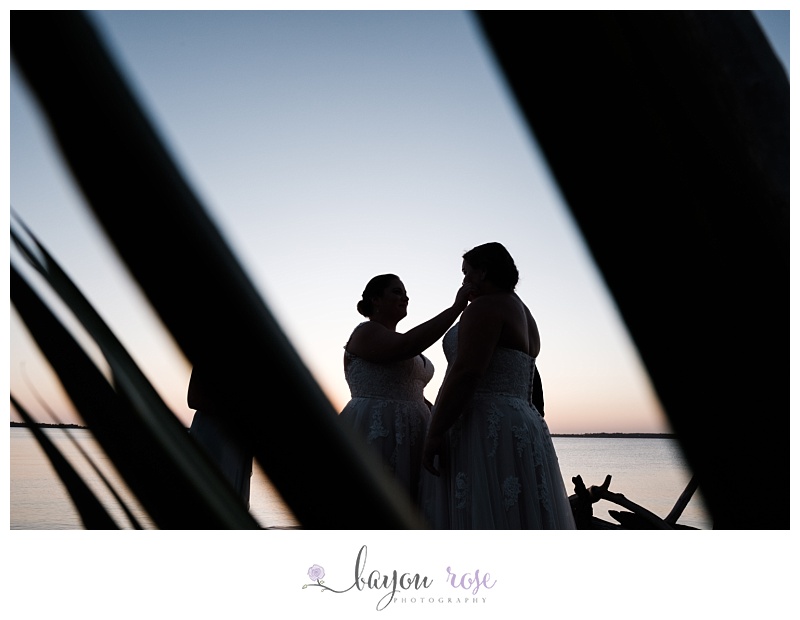 silhouette of two brides at altar against Pensacola sunset sky
