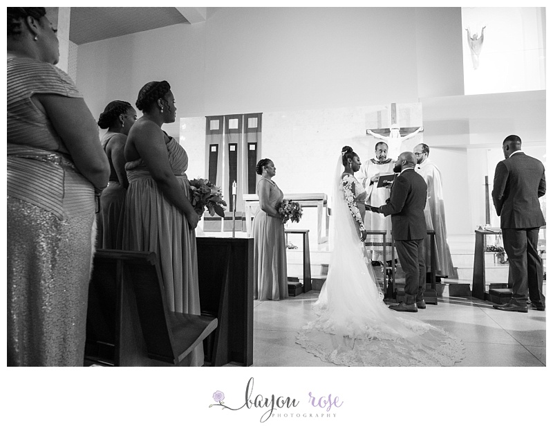 bride and groom exchange rings at altar during ceremony at Transfiguration Church New Orleans