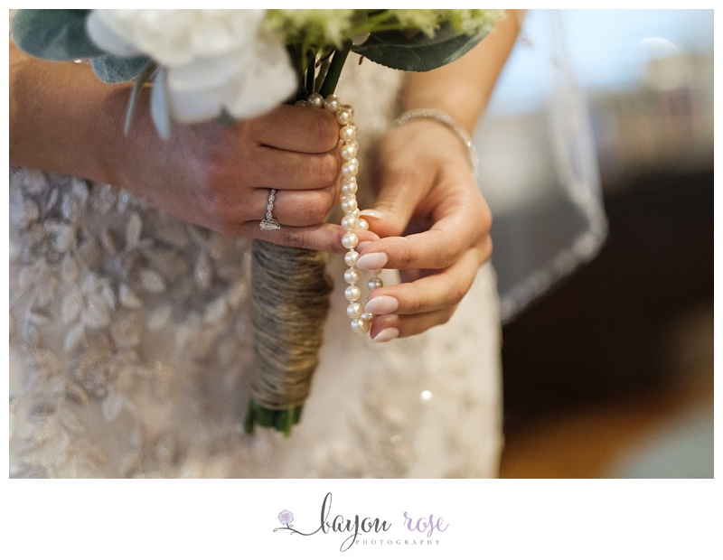 bride playing with grandmother's pearls wrapped around wedding bouquet