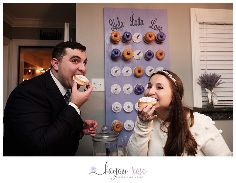bride and groom eating doughnuts from doughnut wall