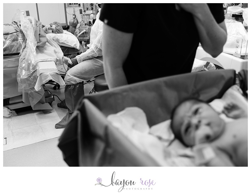 childbirth photography at woman's hospital, mom looking at baby in the operating room