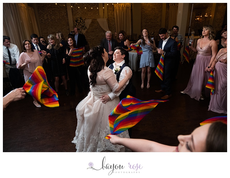 gay wedding couple dancing with pride flags