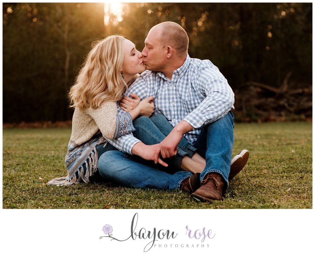 couple kissing under sun flare in outdoor photo session in Baton Rouge
