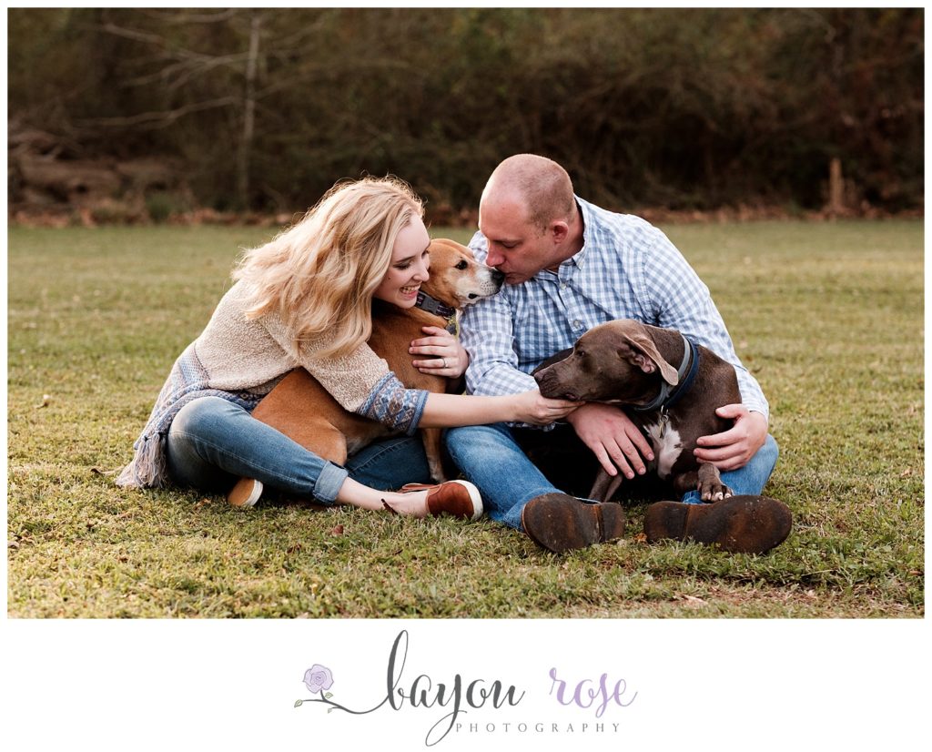 engaged couple hugging their dogs together outside in Baton Rouge location