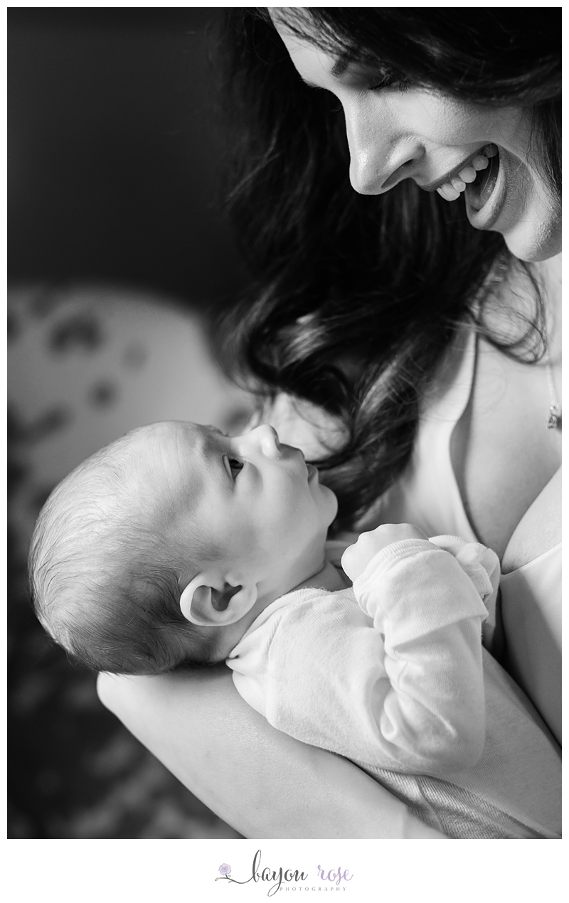 new mom laughing as she holds her newborn baby boy