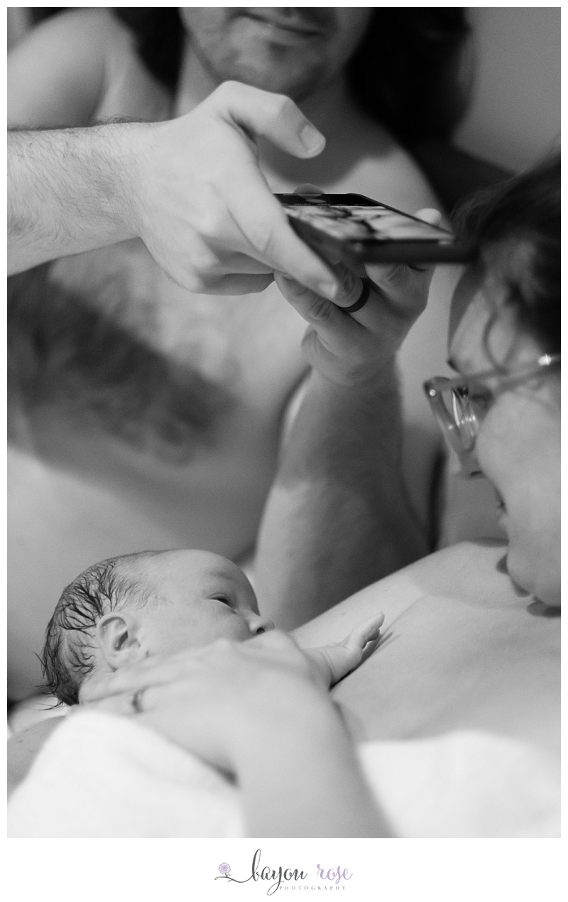 father of newborn taking iphone photo of baby