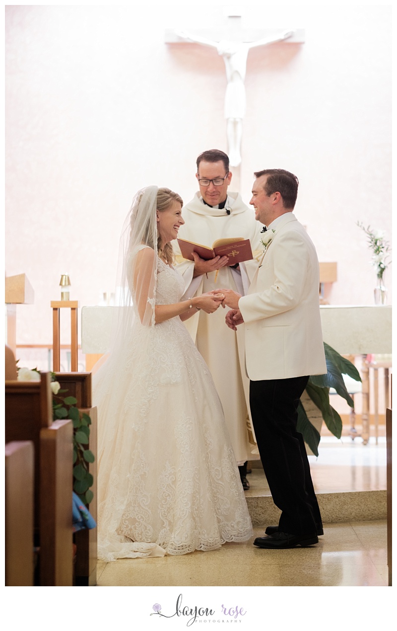 bride and groom laughing at altar as they exchange wedding rings