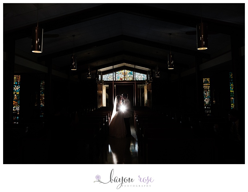 starburst light behind wedding couple in stained glass Catholic cathedral in Baton Rouge