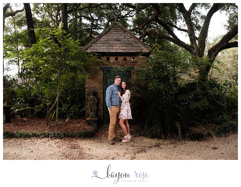 Engaged couple at Windrush Gardens posing in front of cottage