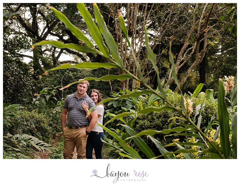 Engaged couple framed by large leaf in garden