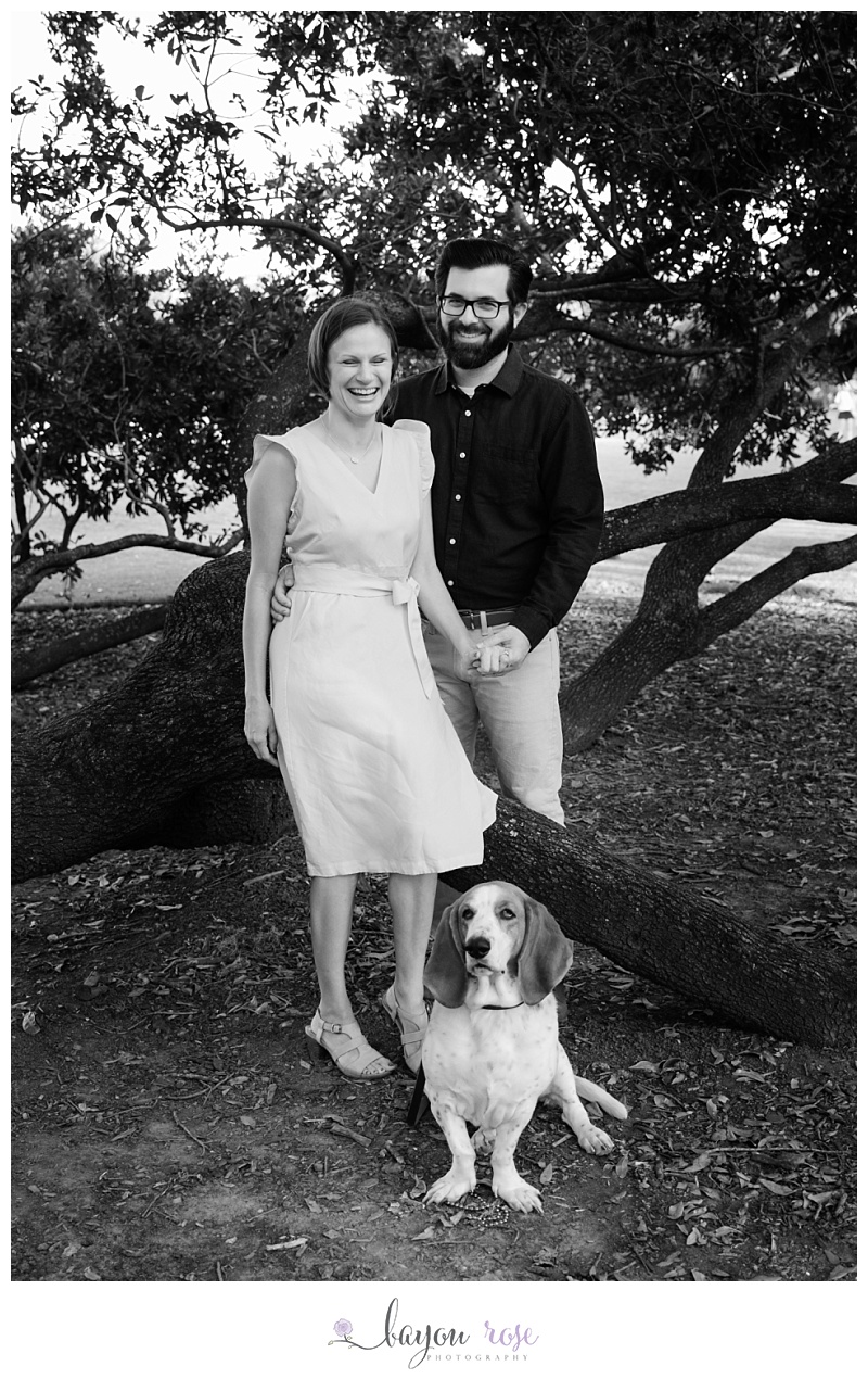 Black and white image of engaged couple laughing at their dog
