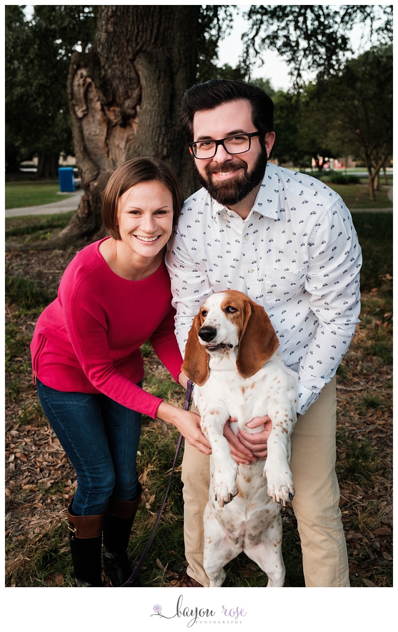 Couple posing for engagement photo with dog who has grumpy look on her face