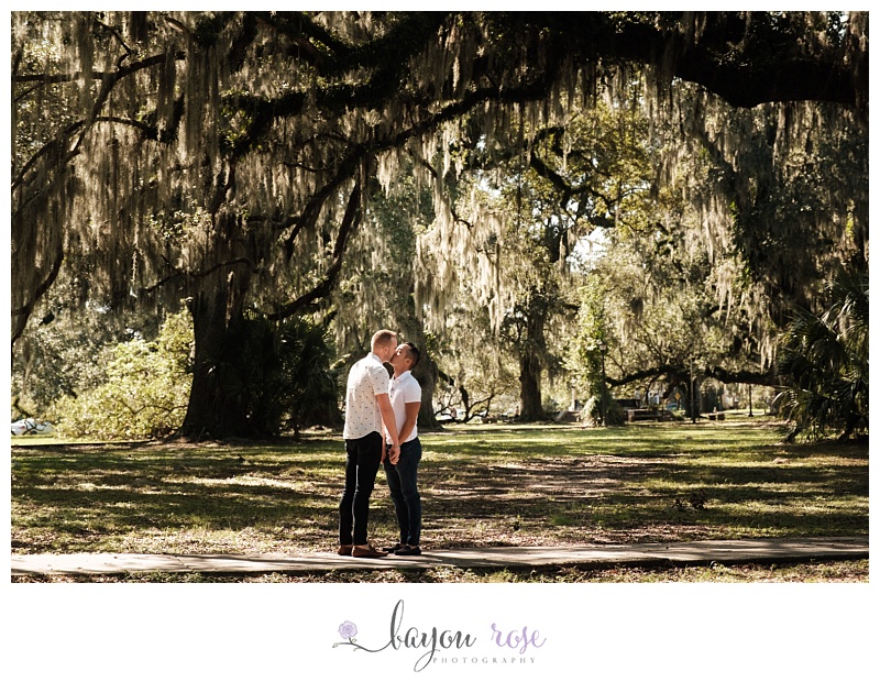 Gay men kissing under Spanish moss and oak trees in City Park New Orleans
