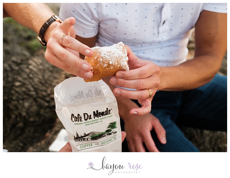 Gay couple showing off engagement rings while holding beignets from Cafe du Monde