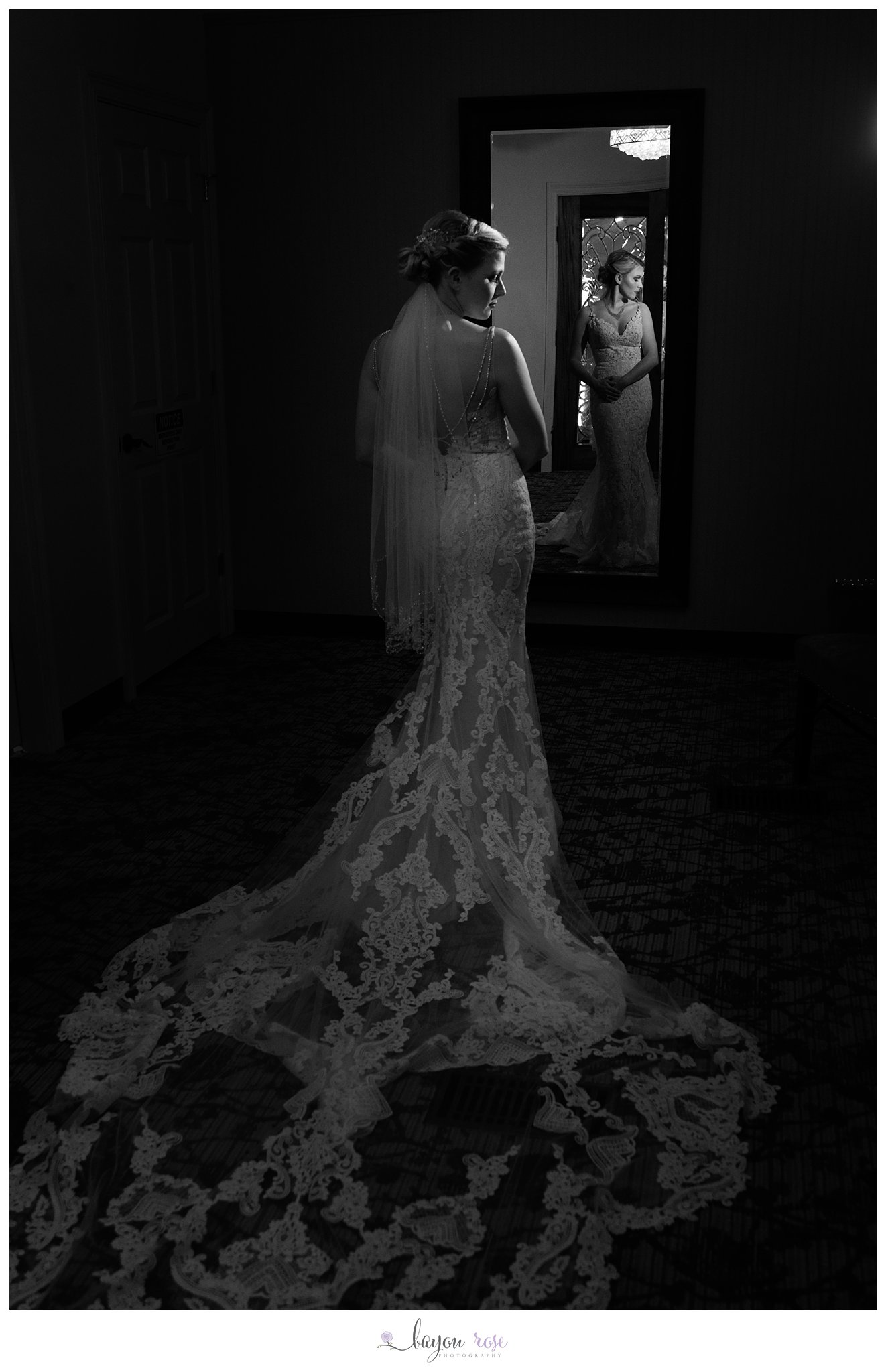 Black and white photo of bride in mirror silhouetted by light