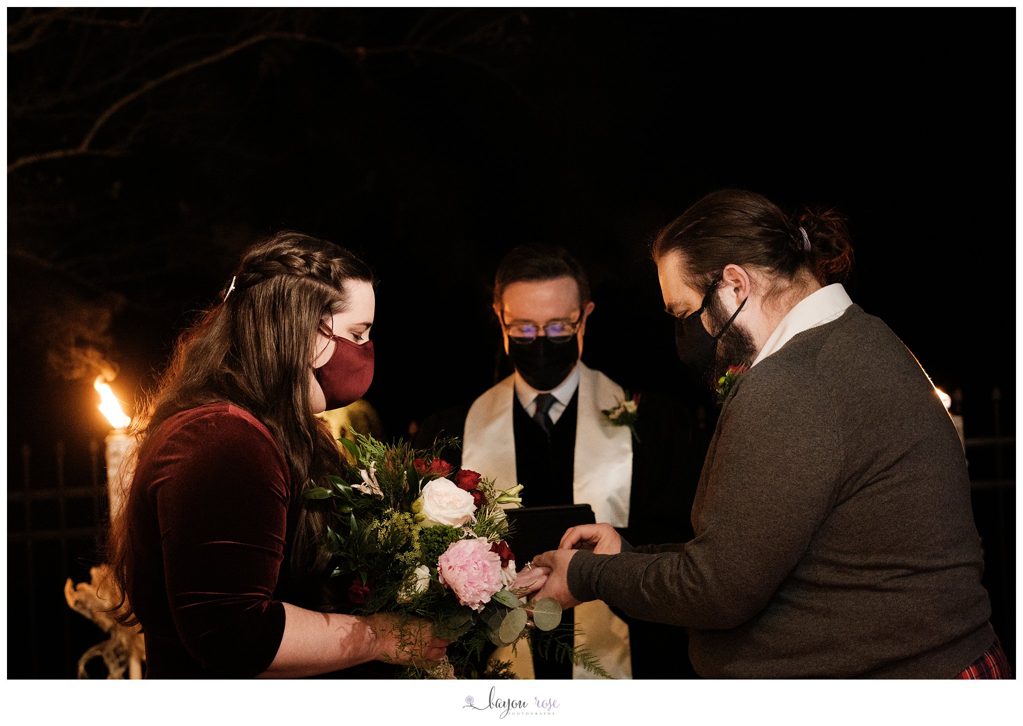 bride and groom exchanging wedding rings while wearing masks for elopement
