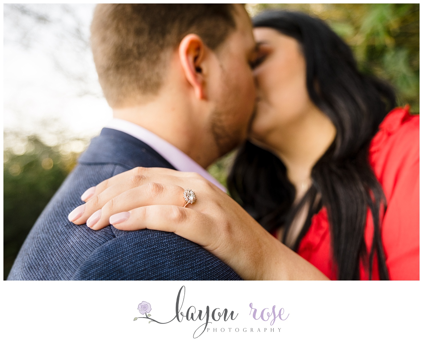 photo of couple kissing in background with engagement ring in focus