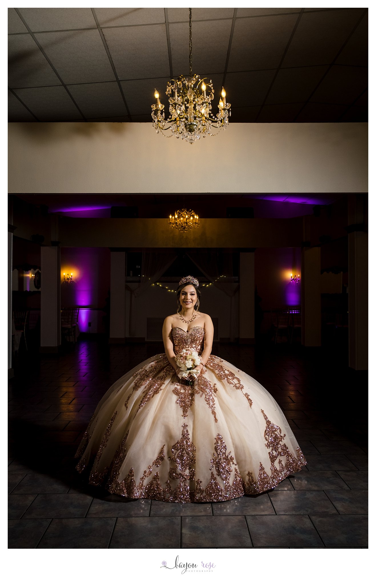 girl poses under chandelier in her quinceanera dress