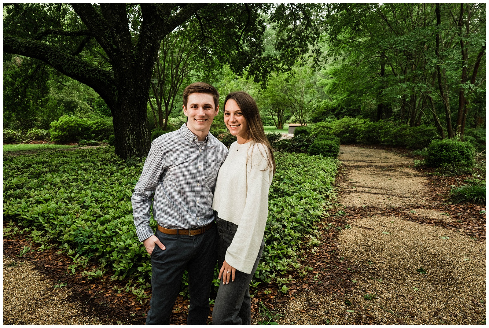 Engaged couple posing under tree at Windrush Gardens