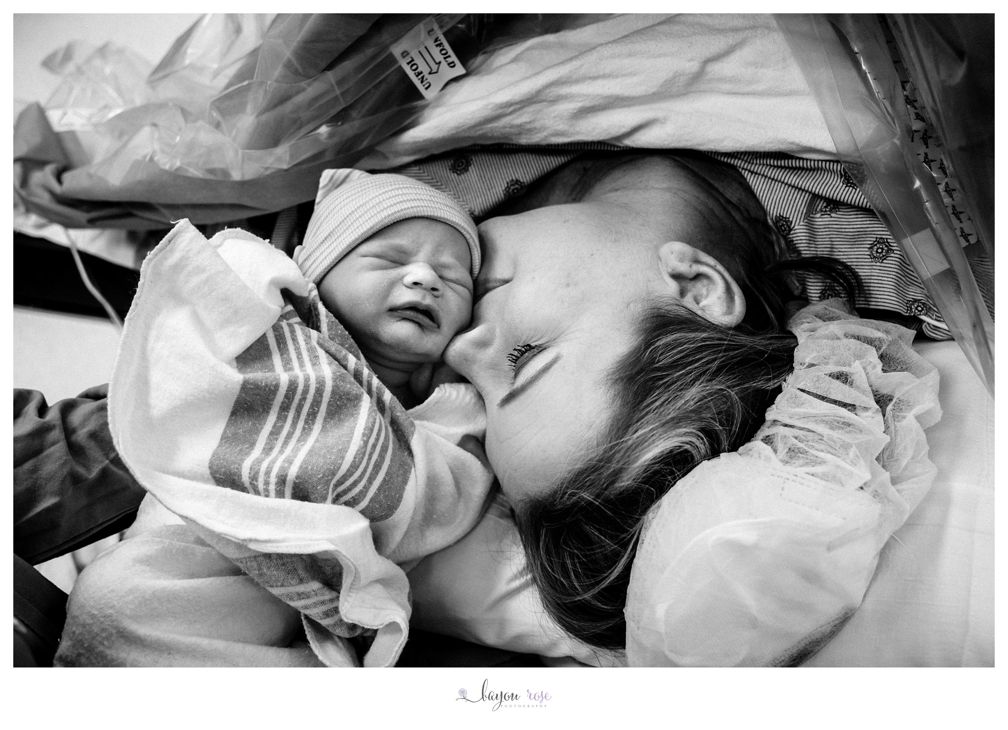 mom kissing newborn baby girl on the cheek