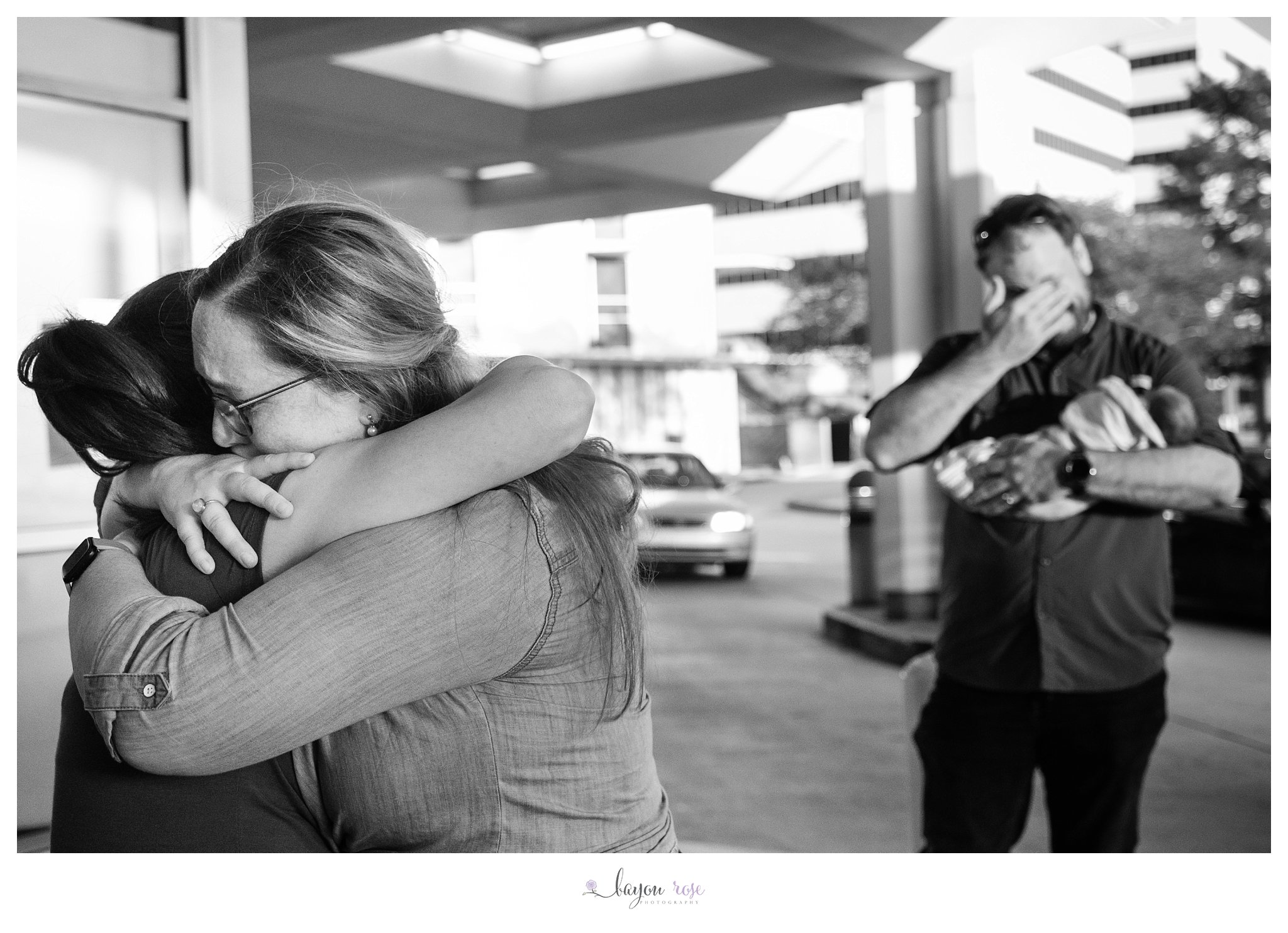 black and white photo of adoptive parents hugging birth mom and crying