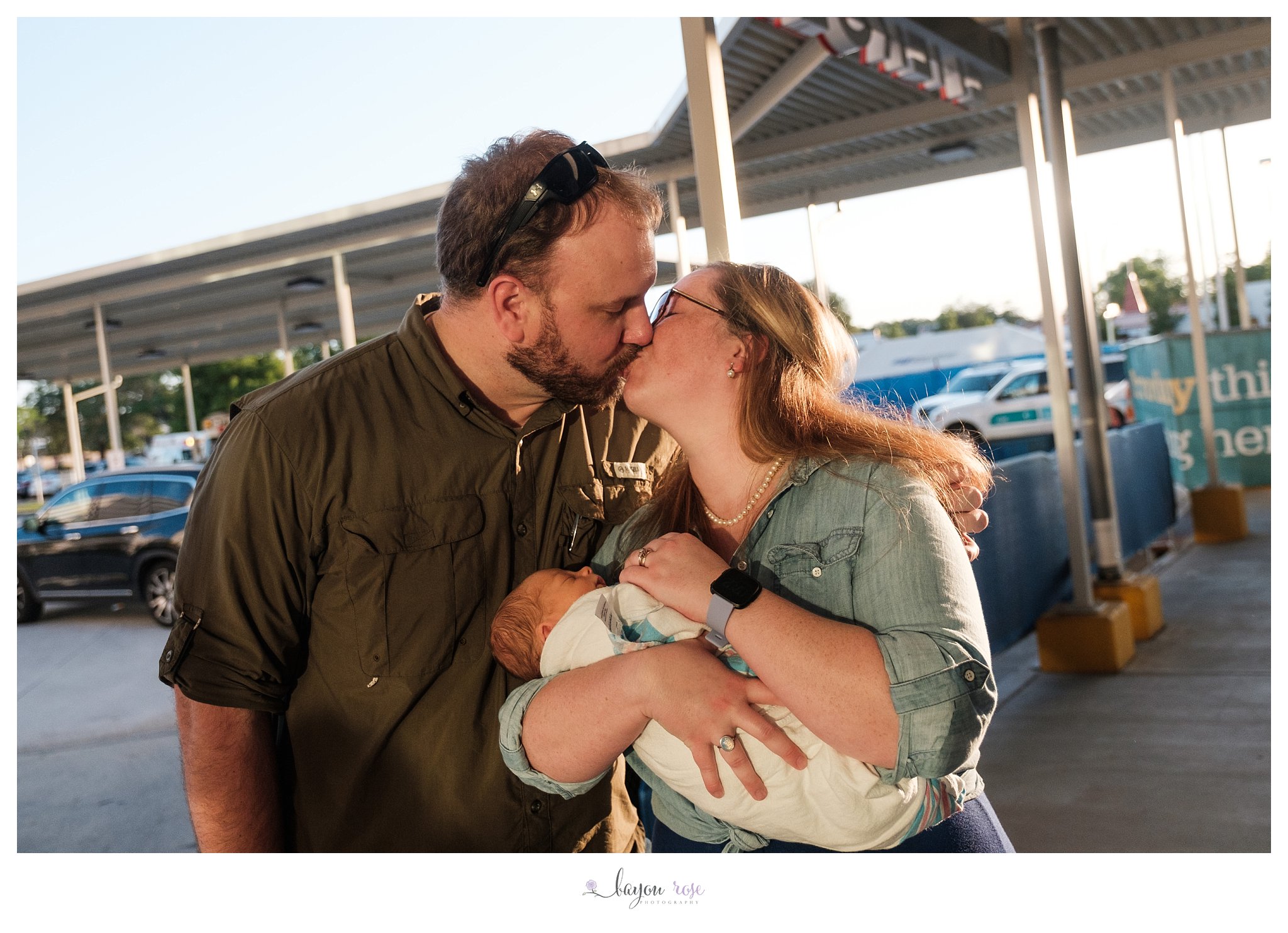 adoptive parents kissing while holding newborn