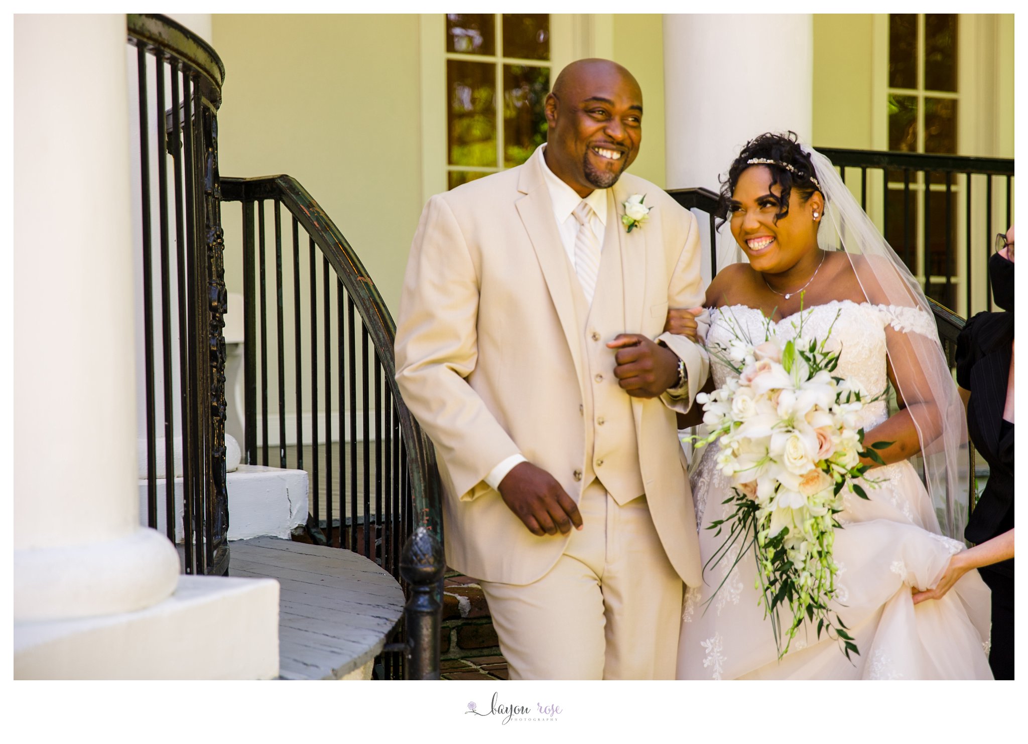 Black bride laughing with her father as he walks her down the aisle