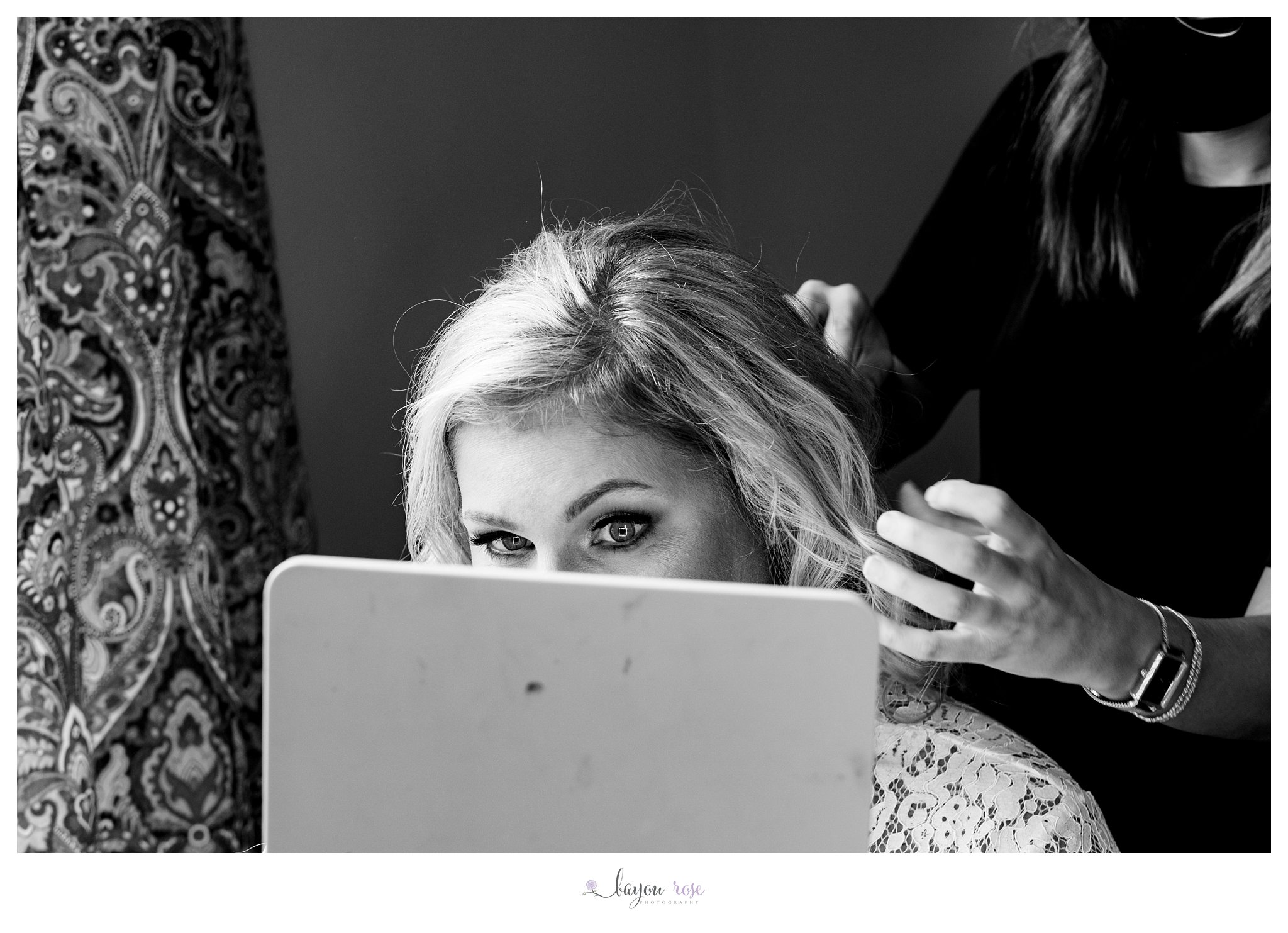 black and white photo of bride checking out her wedding makeup in mirror